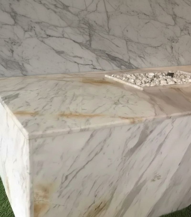 Marble bench showing brown oxidation stains on surface.
